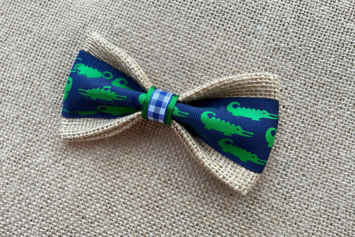 Pet bow tie with green alligator pattern on a blue background.|Nœud papillon pour animal à motif d'alligators verts sur fond bleu.