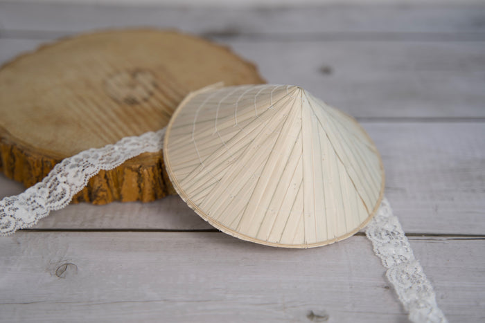 Traditional conical dog hat on a wooden surface with lace trim.|Chapeau conique traditionnel pour chien, posé sur une surface en bois et orné d'une bordure en dentelle.