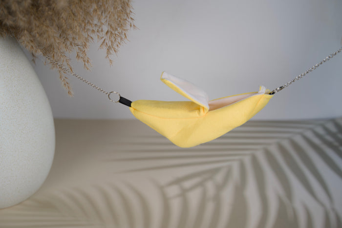 Yellow hammock for small animals suspended from a chain with an opening at the top.|Hamac jaune pour petits animaux suspendu à une chaîne avec ouverture dans le haut.