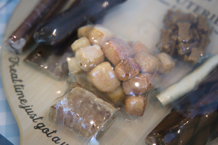 Assorted charcuterie dog treats for items on a plate with text.|Friandises pour chiens assorties à base de charcuterie, présentées sur une assiette avec du texte.