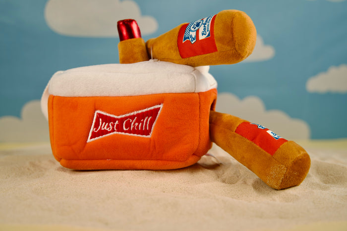 Dog playing with plush beer cooler toy and squeaky bottles.|Chien jouant avec une glacière en peluche et des bouteilles qui couinent.