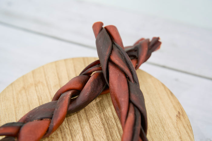Close-up view of the two braided dog collagen chew treats, reddish-brown.|Gros plan sur les deux friandises à mâcher tressées au collagène pour chiens, de couleur brun-rouge.