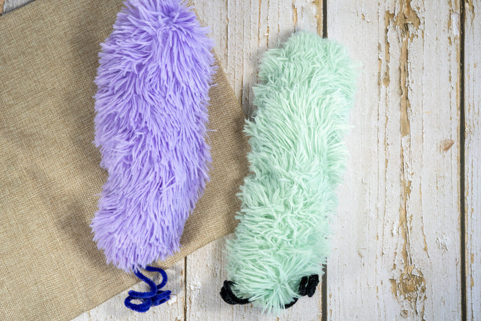 Plush cat toy in the shape of a giant caterpillar in pastel colors and long hair filled with catnip. | Peluche pour chat en forme de chenille géante aux couleurs pastel et aux poils longs remplis d'herbe à chat.