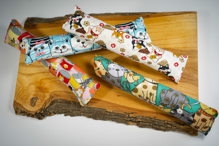 Cotton cat toy pillow filled with catnip and with bright and fun patterns. | Oreiller jouet pour chat en coton rempli d'herbe à chat et avec des motifs lumineux et amusants.