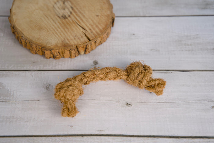 Coconut knotted rope dog toy on a light wooden surface.|Jouet pour chien en corde nouée et coco, posé sur une surface en bois clair.