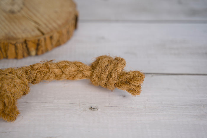 Coconut rope dog toy on a wooden surface.|Jouet pour chien en corde de coco sur une surface en bois.