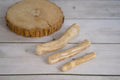 Three coffee wooden sticks dog toy on a light wooden surface.|Trois jouets pour chien en bois de café, posés sur une surface en bois clair.