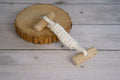 Wooden dog toy with a cotton rope on a wooden surface.|Jouet en bois pour chien avec une corde en coton, posé sur une surface en bois.