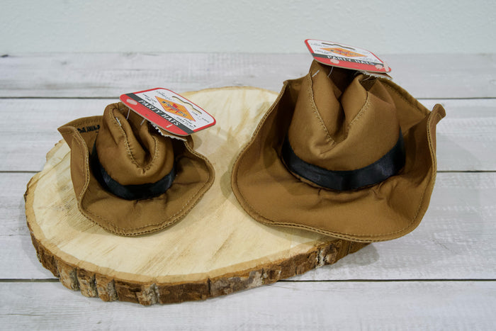 Two dog cowboy party hats with black bands on a wooden surface.|Deux chapeaux de cowboy pour chien avec des bandes noires, posés sur une surface en bois.