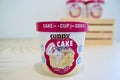 Cuppy Cake birthday cake flavour microwaveable dog cake in a cup with pink lid on a white background.|Cuppy Cake, gâteau d'anniversaire pour chien à cuire au micro-ondes dans une tasse, avec couvercle rose, sur fond blanc.