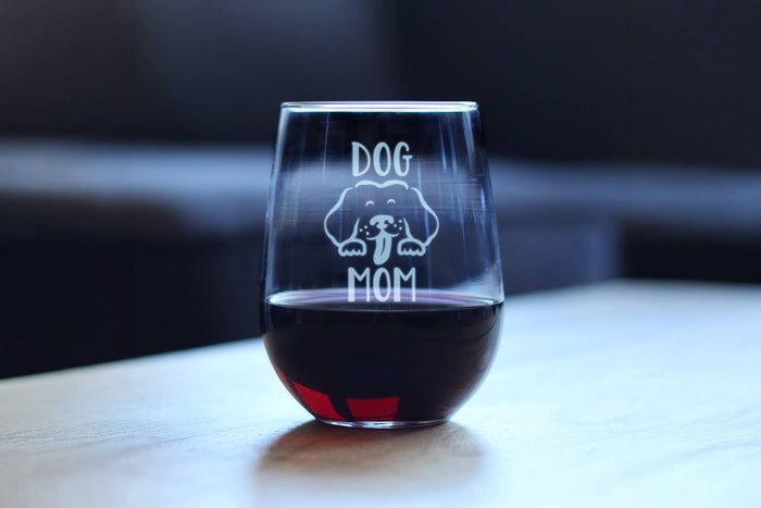Stemless wine glass with 'DOG MOM' engraving on a table.|Verre à vin sans pied gravé « DOG MOM » posé sur une table.