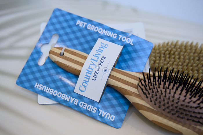 Wooden pet grooming brush with County Living tag on a blue card.|Brosse de toilettage pour animaux en bois avec étiquette County Living sur une carte bleue.