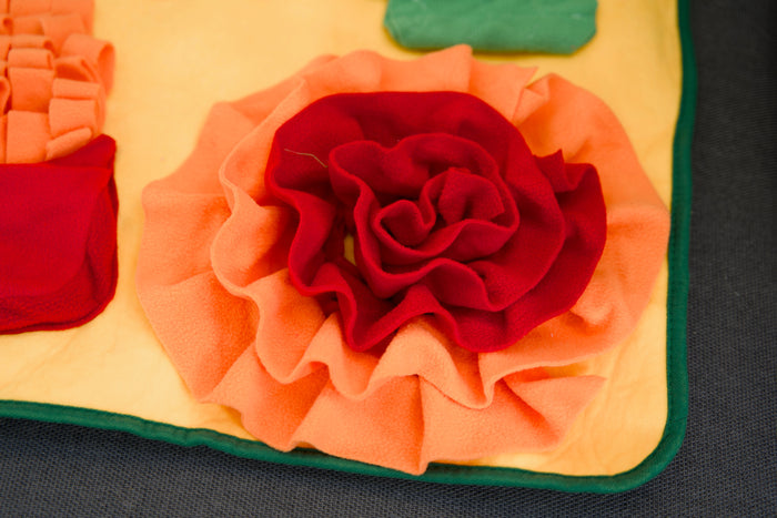 Close-up of a colorful fabric flower on a textured surface.Gros plan d'une fleur en tissu coloré sur une surface texturée.