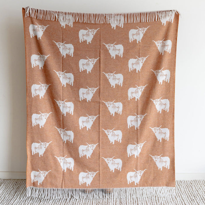 Brown blanket with white cow pattern on a light gray surface