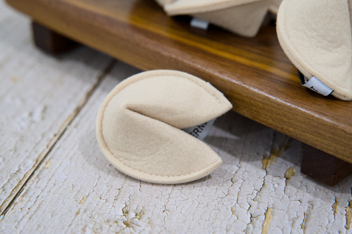 Close-up of a felt cat toy shaped like a fortune cookie.|Gros plan sur un jour pour chats en forme de biscuits chinois en feutre.