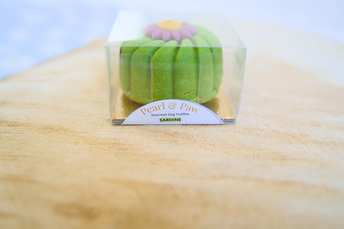 Sardine gourmet dog truffle in a clear packaging on a wooden surface.|Des croquettes pour chiens au goût de sardine et de truffe, présentées dans un emballage transparent sur une surface en bois.