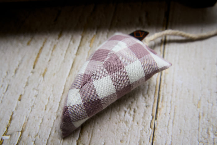 A modern cat toy mouse filled with catnip resting on a rustic white wooden surface.|Une souris-jouet moderne pour chat, remplie d'herbe à chat, posée sur une surface en bois blanc rustique.