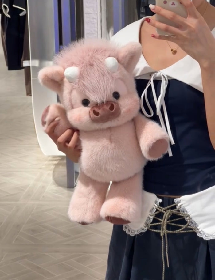 Person holding a pink cow plush  toy in front of a mirror.