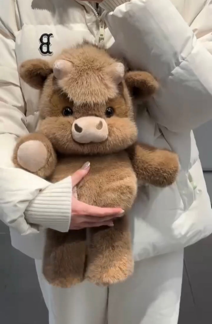 Brown cow plushie held by a person wearing a white coat.