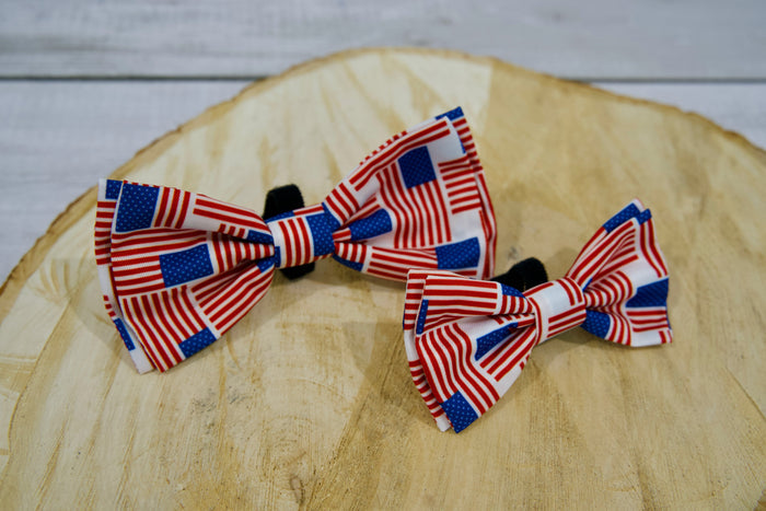 Two American flag-themed pet bow ties on a wooden surface.|Deux nœuds papillon pour animaux aux motifs du drapeau américain, posés sur une surface en bois.