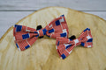 Two American flag-themed pet bow ties on a wooden surface.|Deux nœuds papillon pour animaux aux motifs du drapeau américain, posés sur une surface en bois.