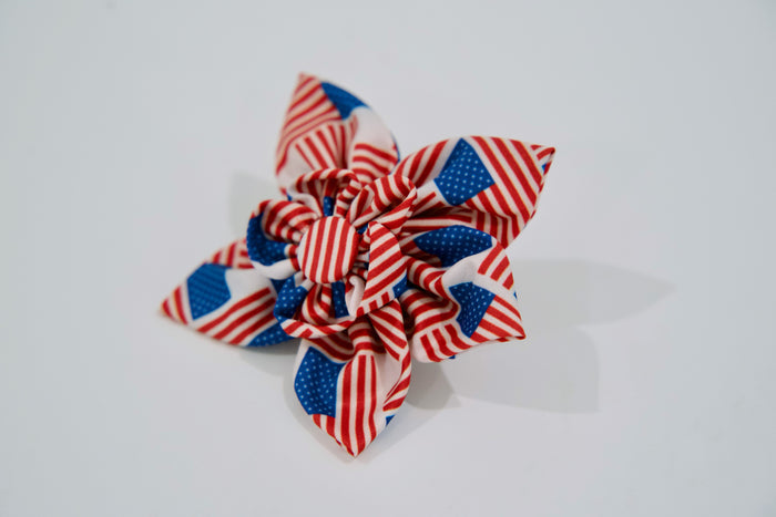 Decorative pet bow with American flag pattern on a white background.|Nœud décoratif pour animaux avec un motif de drapeau américain sur fond blanc.