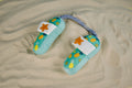 The playful dog slipper toy rests on warm sand, ready for beachside tugging and tail-wagging fun. | Le jouet pantoufle pour chien repose sur le sable chaud, prêt pour des jeux de tir à la plage et des moments de plaisir à remuer la queue.