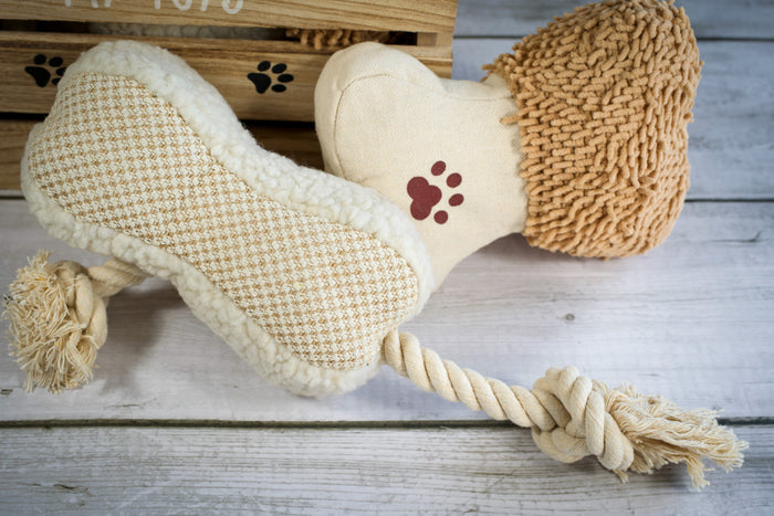 Close-up view of two bone-shaped plush and rope dog toys. | Vue rapprochée de deux jouets pour chiens en peluche et en corde en forme d'os.