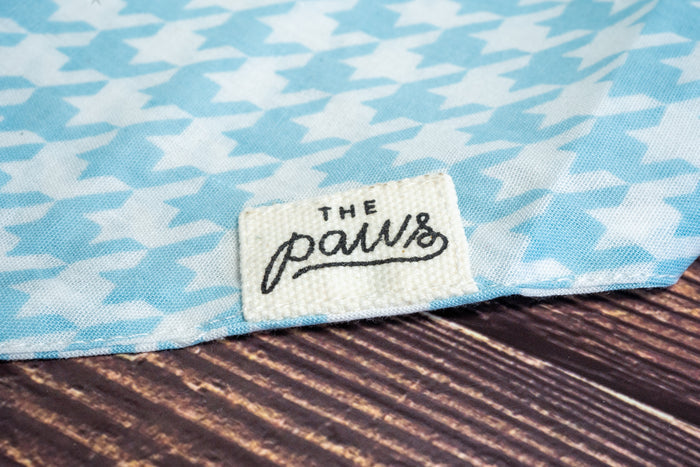 Close-up of The Paws logo on dog bandana with steele patterns.|Gros plan sur le logo The Paws sur bandana pour chien avec motifs de pied-de-poule.