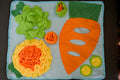 Rabbit snuffle mat with giant carrots for hay and other elements imitating a vegetable garden.|Tapis de reniflement pour lapins avec carottes géantes pour foin et autres éléments imitant un potager.