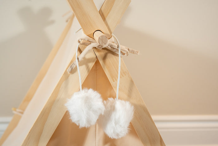 Close-up view of the super soft white decorative pom poms of the beige pet tent. | Vue rapprochée des pompons décoratifs blancs super doux de la tente beige pour animaux.