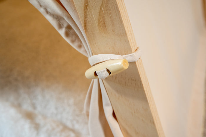 Close-up view of beige pet tent curtain clip. | Vue rapprochée de l'attache à rideaux de la tente beige pour animaux.